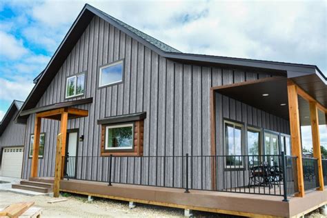 grey metal house with green roof|gray siding black windows.